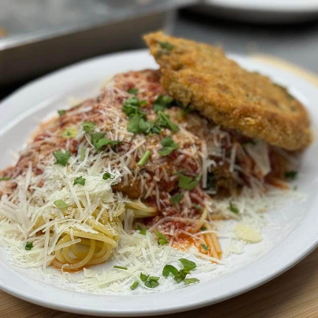 Chicken Parmigiana over pasta (Penne).